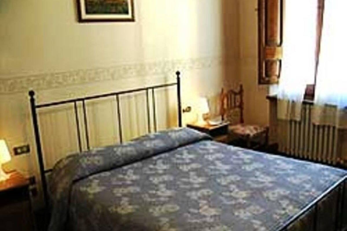 A bedroom with a bed, a nightstand, a chair, and a radiator.