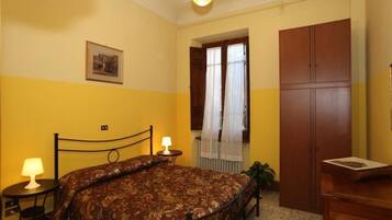 A bedroom with a bed, bedside tables, a wardrobe, and a window with curtains.