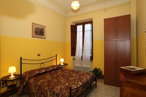 A bedroom with a bed, bedside tables, a wardrobe, and a window with curtains. - B&B Santa Chiara (Sulmona)