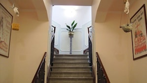Una escalera con barandilla, una planta en maceta en la parte superior y cuadros en las paredes.