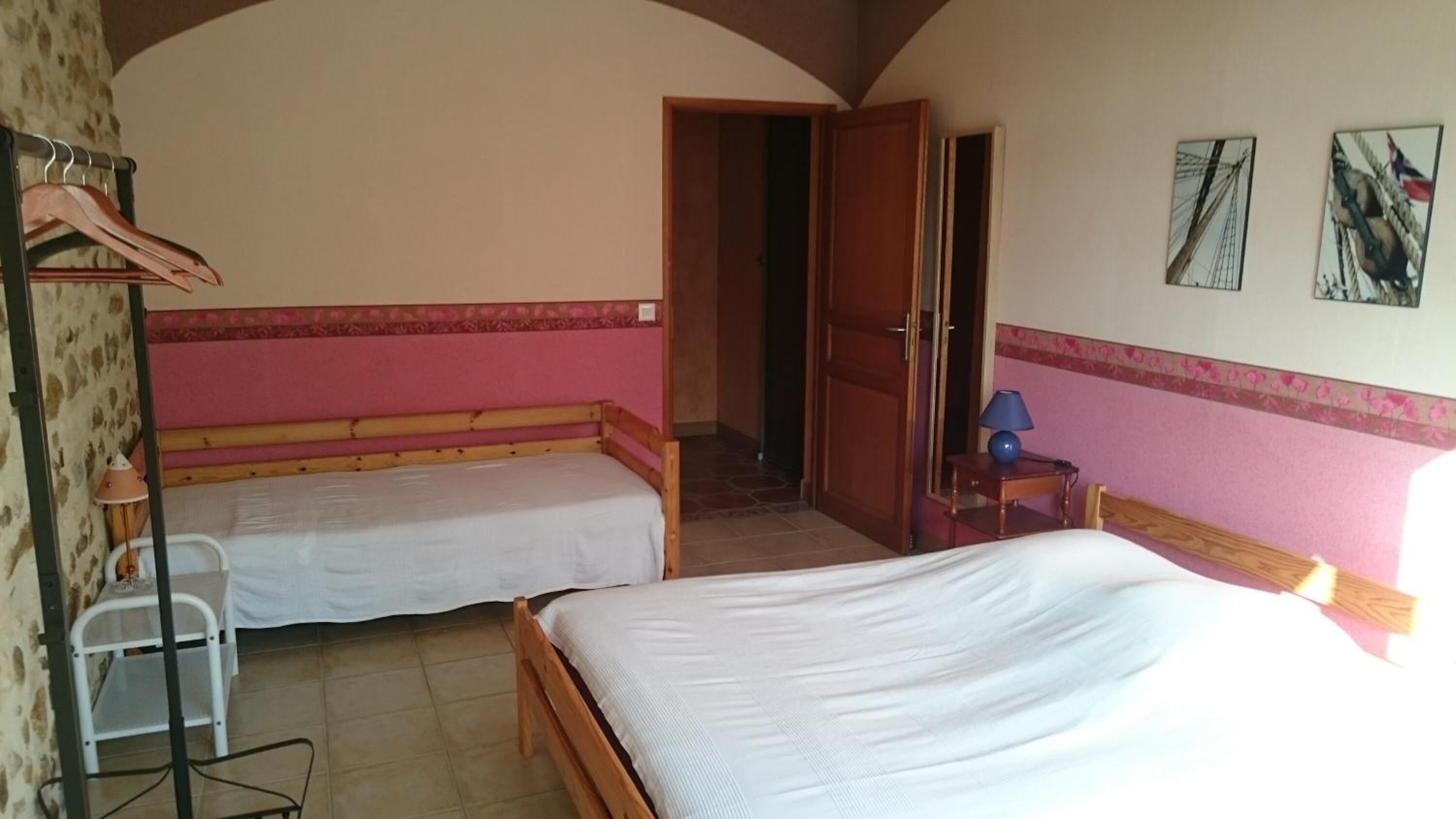 Une chambre avec deux lits simples, une petite table avec une lampe, une chaise et une armoire.