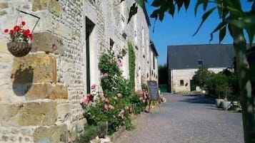 A stone building with a gravel path leading to a larger structure.