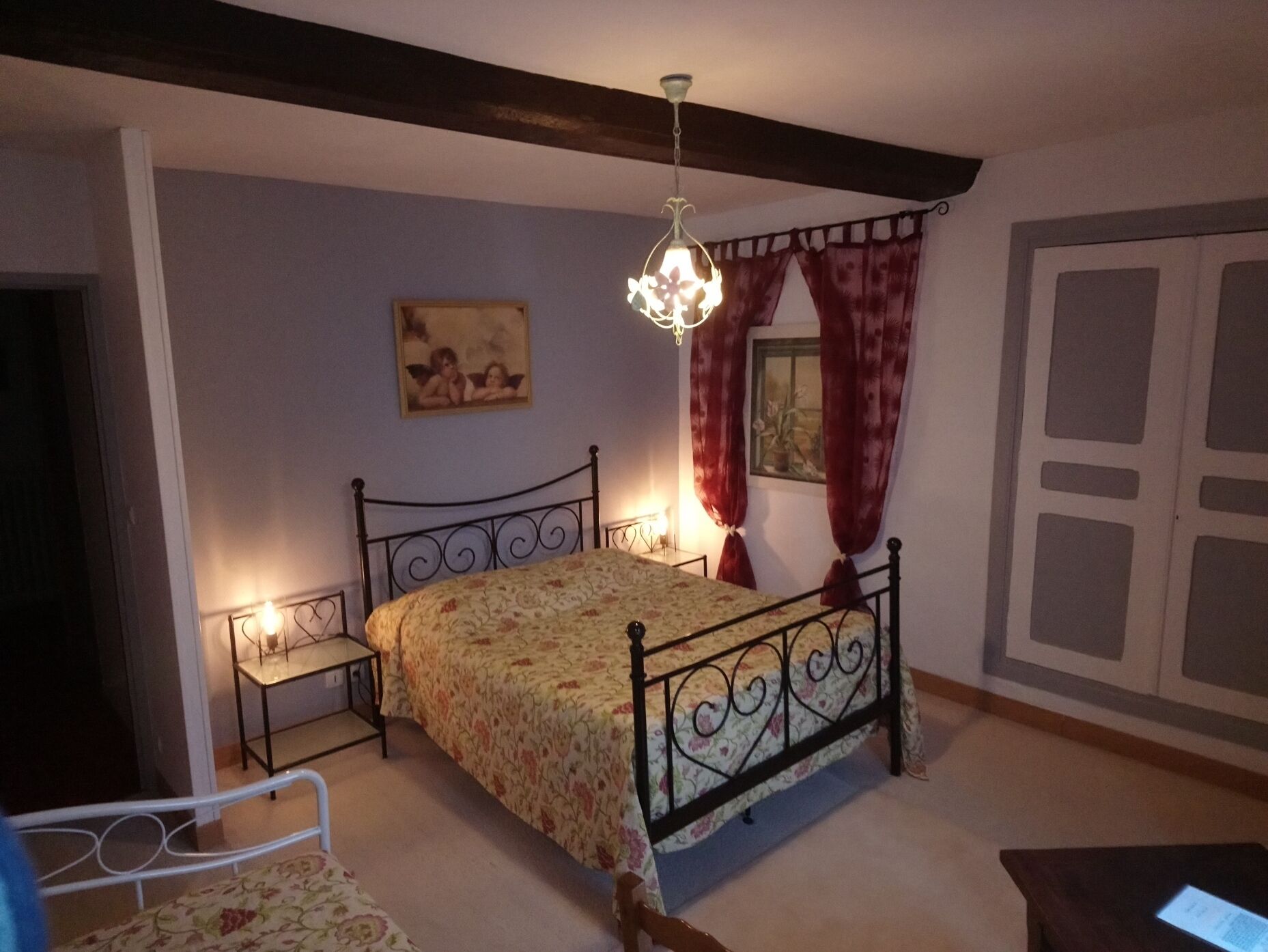 Ein Schlafzimmer mit Bett, Nachttisch, Sessel, einer Deckenleuchte und einem Kleiderschrank.