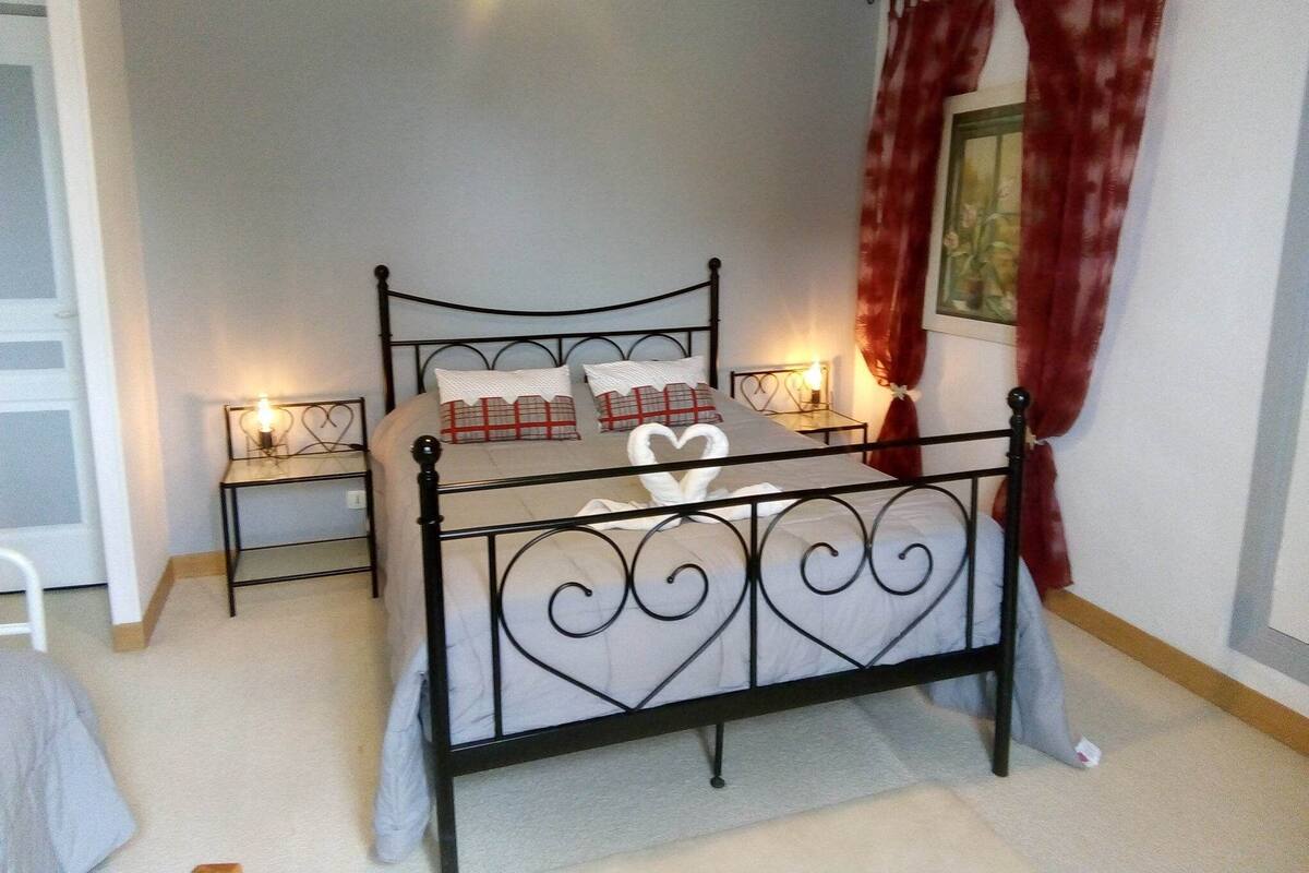 A bedroom with a black metal bed frame, a white bedspread, and two bedside tables with lamps.