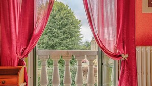 Un balcon avec des balustrades blanches et des rideaux rouges.