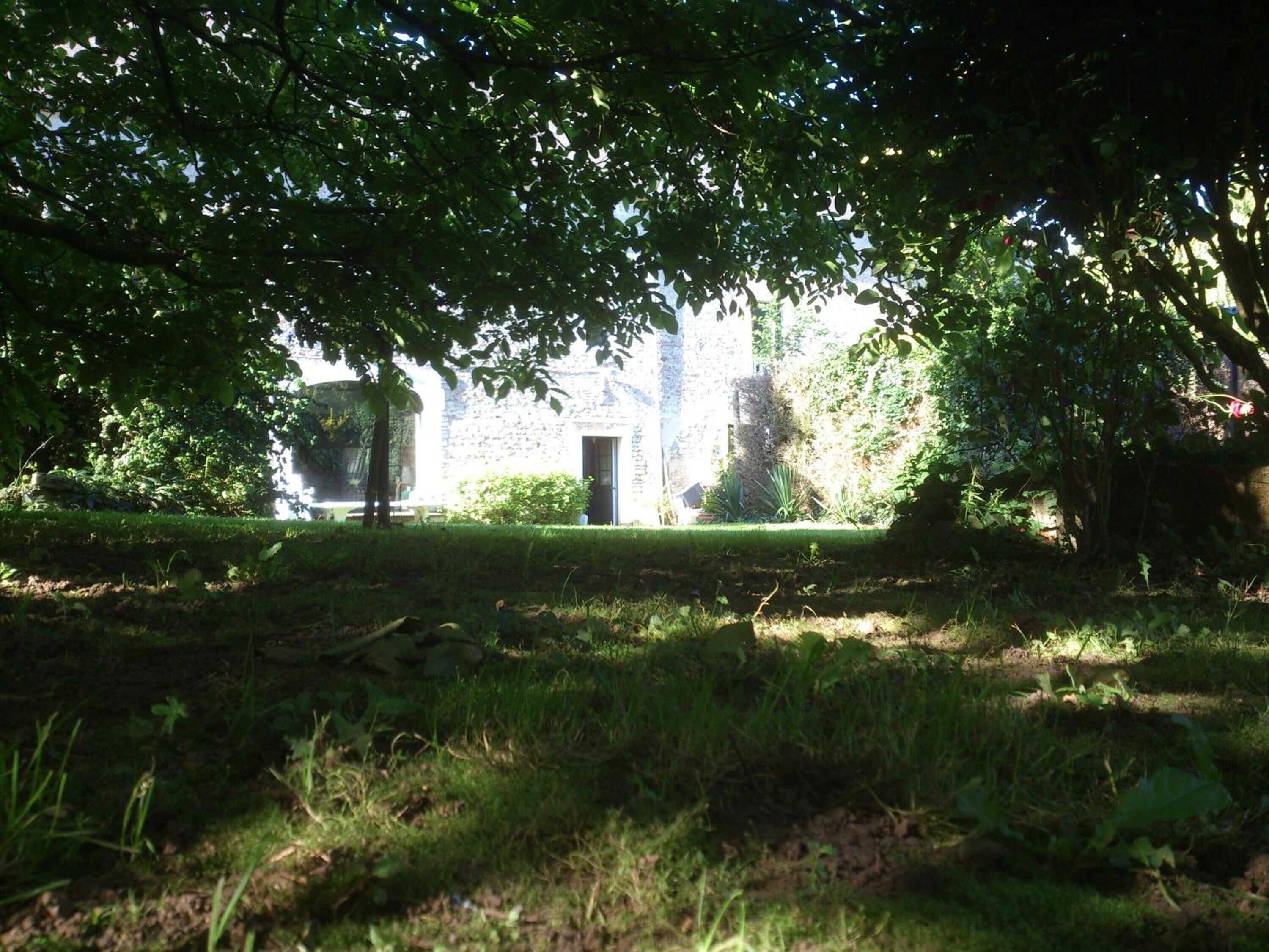 A stone building with a door, surrounded by lush greenery and trees.
