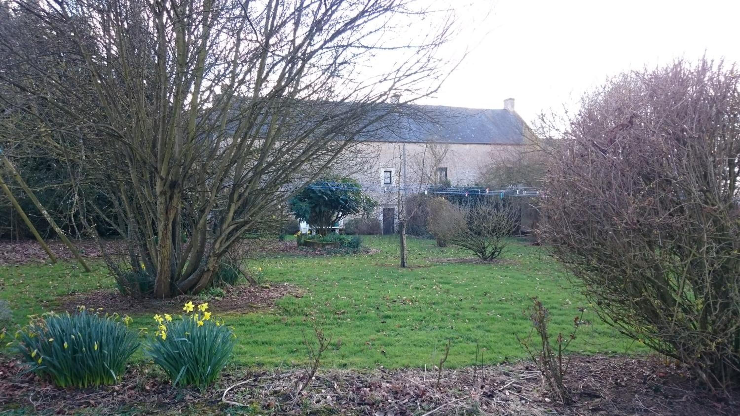 Ein Haus mit Garten, Rasen und einem kleinen Baum.
