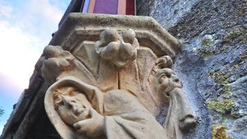 A stone carving of a figure holding a staff and a book, with a window above it.