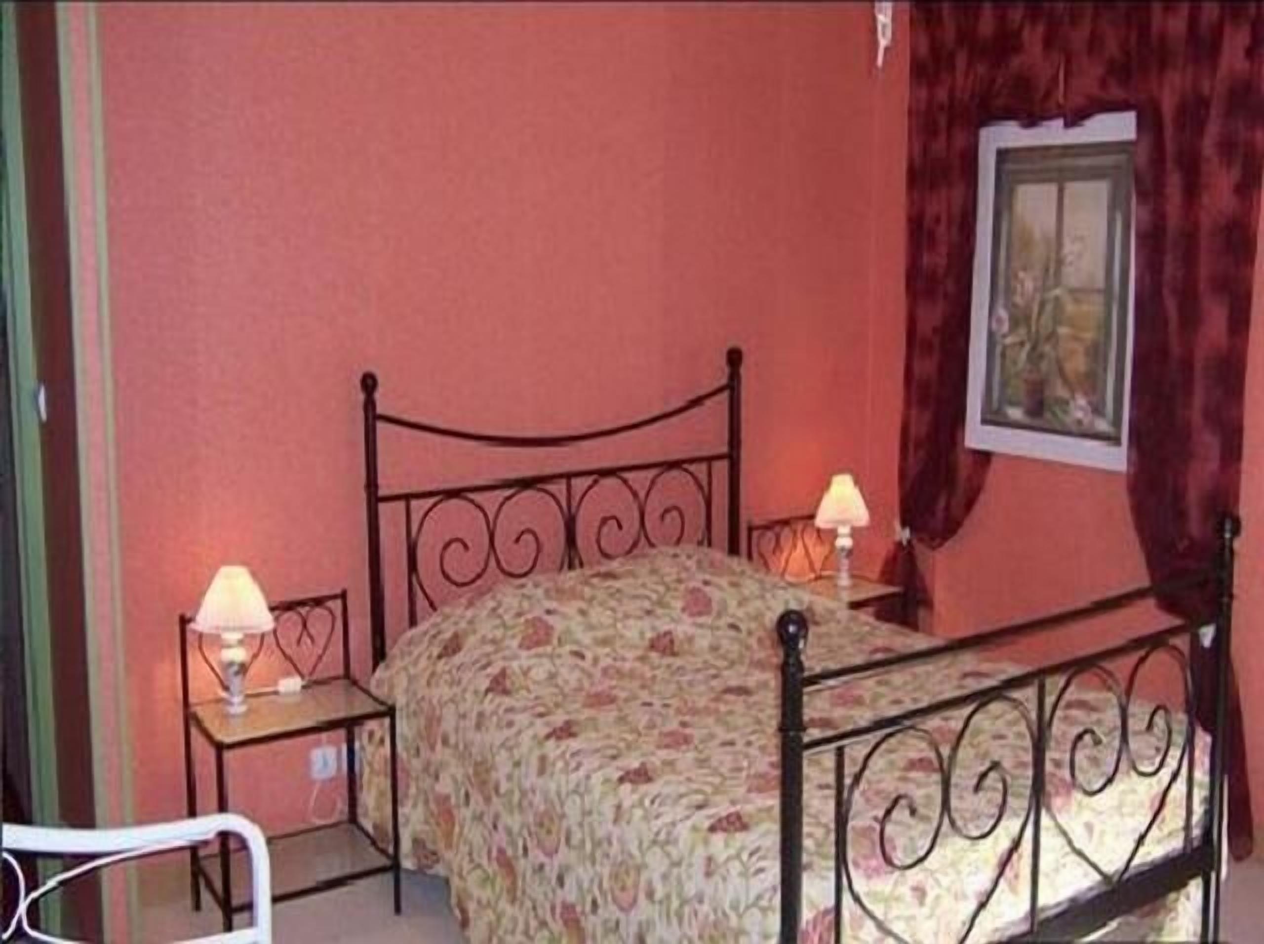 Un dormitorio con una cama, dos lámparas de noche, una silla y un cuadro en la pared.