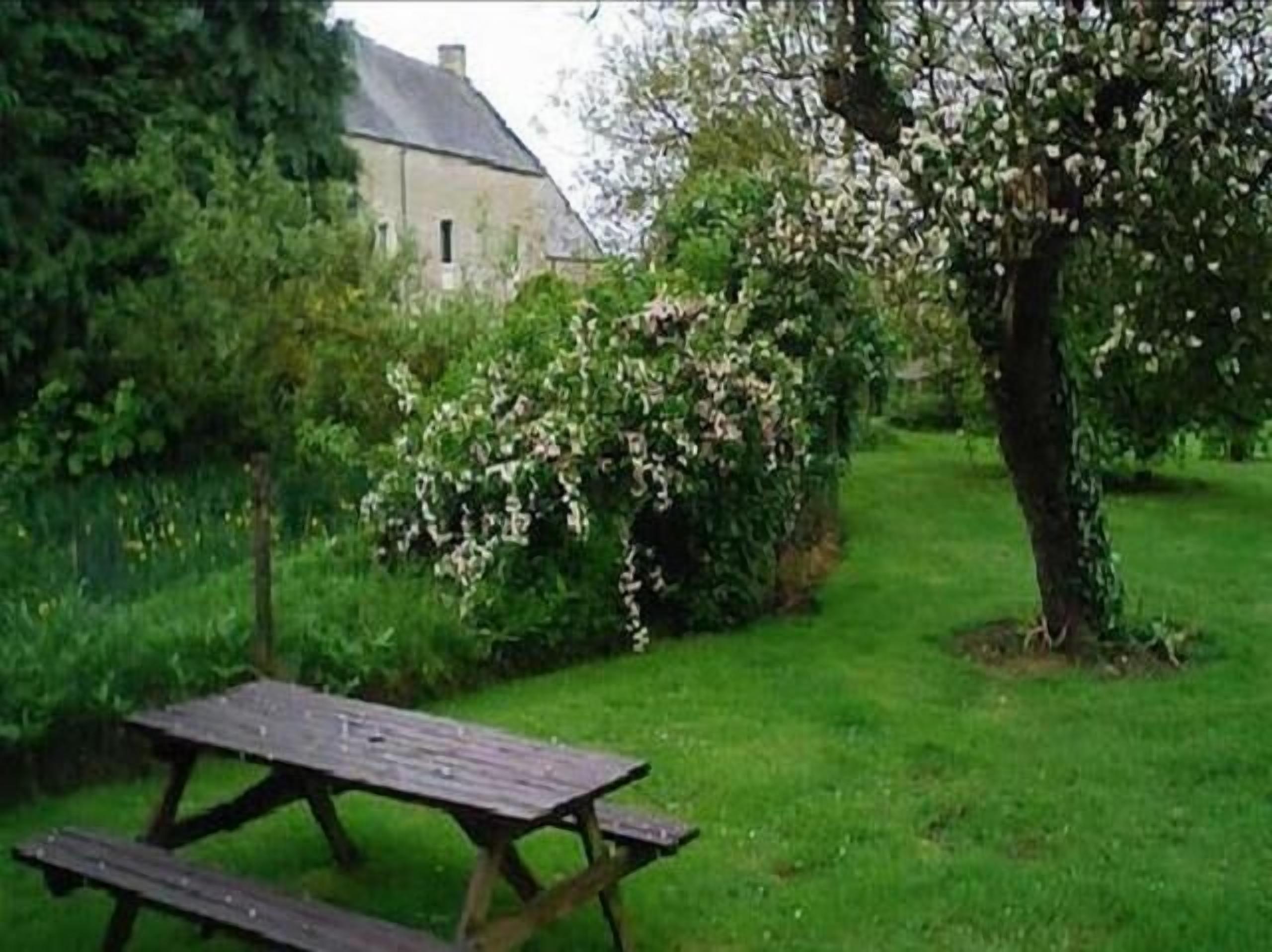 Une table de pique-nique dans un jardin, avec une maison en arrière-plan.