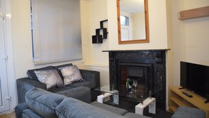 A living room with a fireplace, a sofa, a coffee table, and a television. - People Boxes Apartments - 38 Ridgway (Luton)