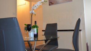 A dining area with a glass table, two chairs, a bottle of wine, and a glass. - People Boxes Apartments - 38 Ridgway (Luton)