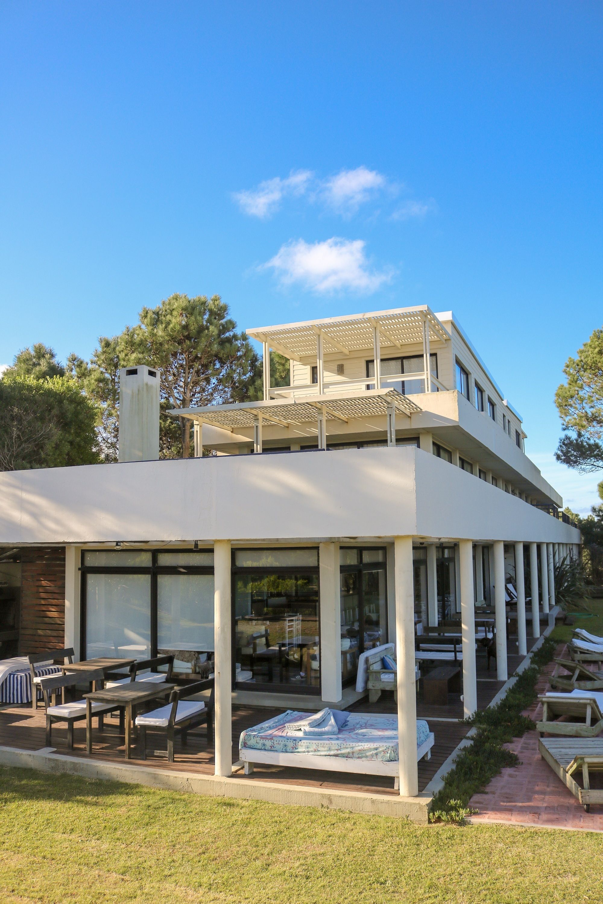 Un bâtiment moderne à deux étages doté d’un patio couvert comprenant un espace salon extérieur et une piscine.