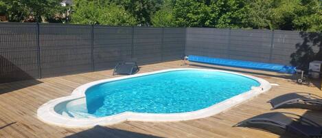 Ein rechteckiger Swimmingpool mit einer Holzterrasse und einer blauen Auskleidung.