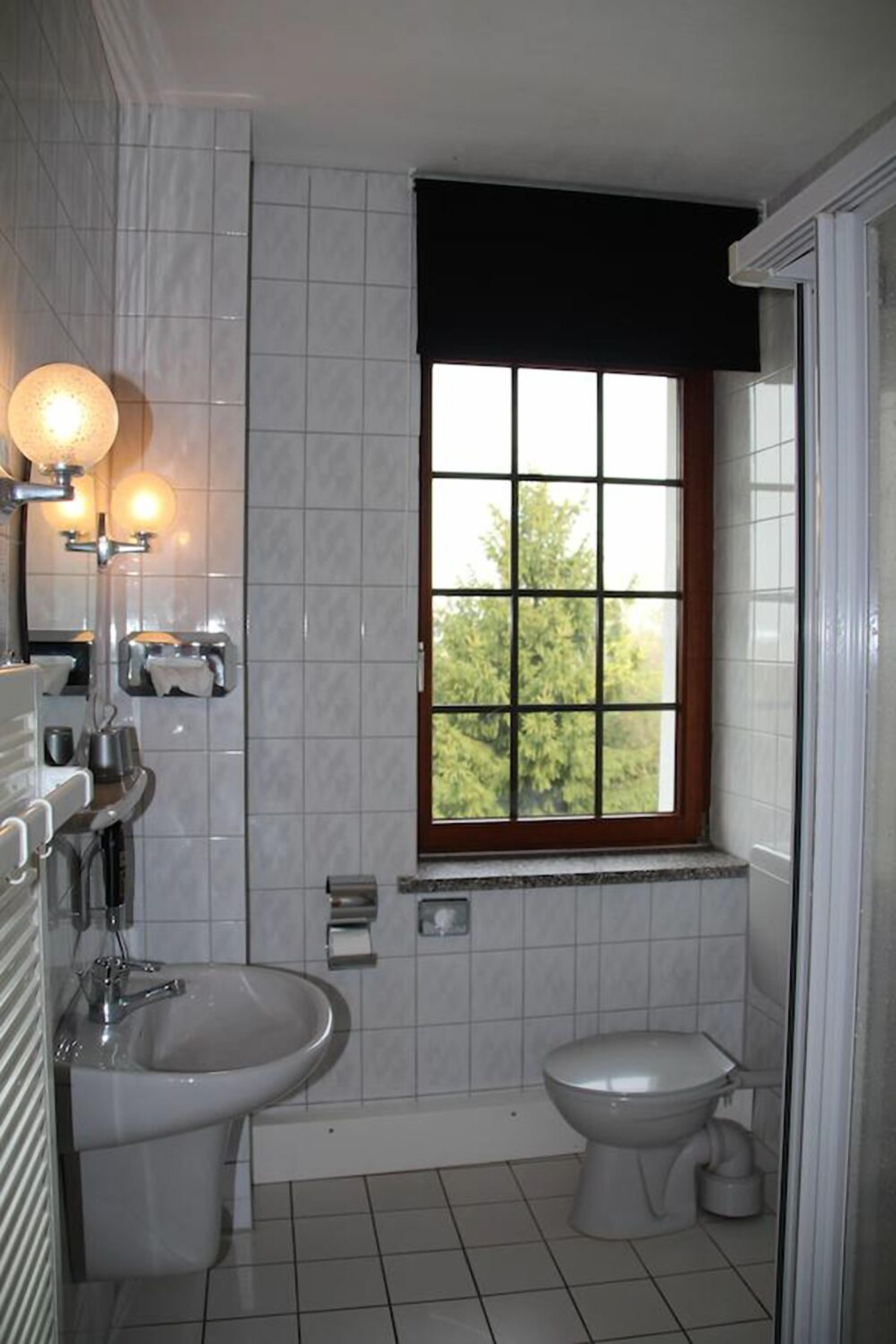 Une salle de bain avec une fenêtre, un lavabo, un bidet et des toilettes.