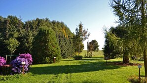 A well-maintained garden with various trees and shrubs, a clear path, and informational signs. - Landhotel Kertscher-Hof (Nobitz)