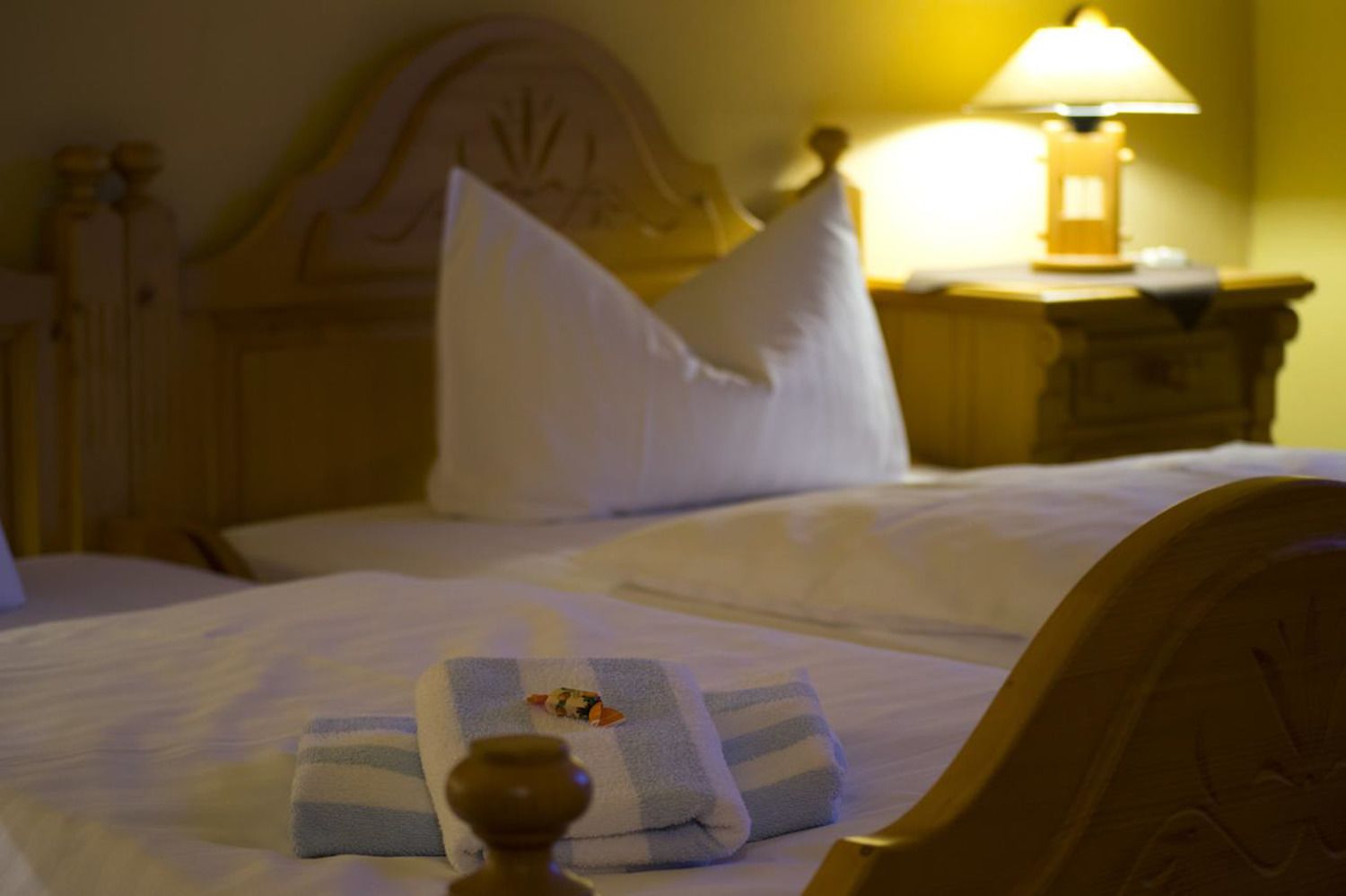 A bed with white bedding, a striped towel, and a small decorative item.