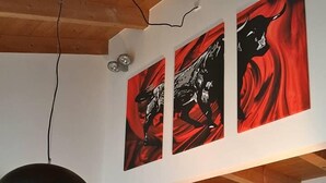 A modern kitchen with a black and red color scheme, wooden beams, and a glass dining table.
