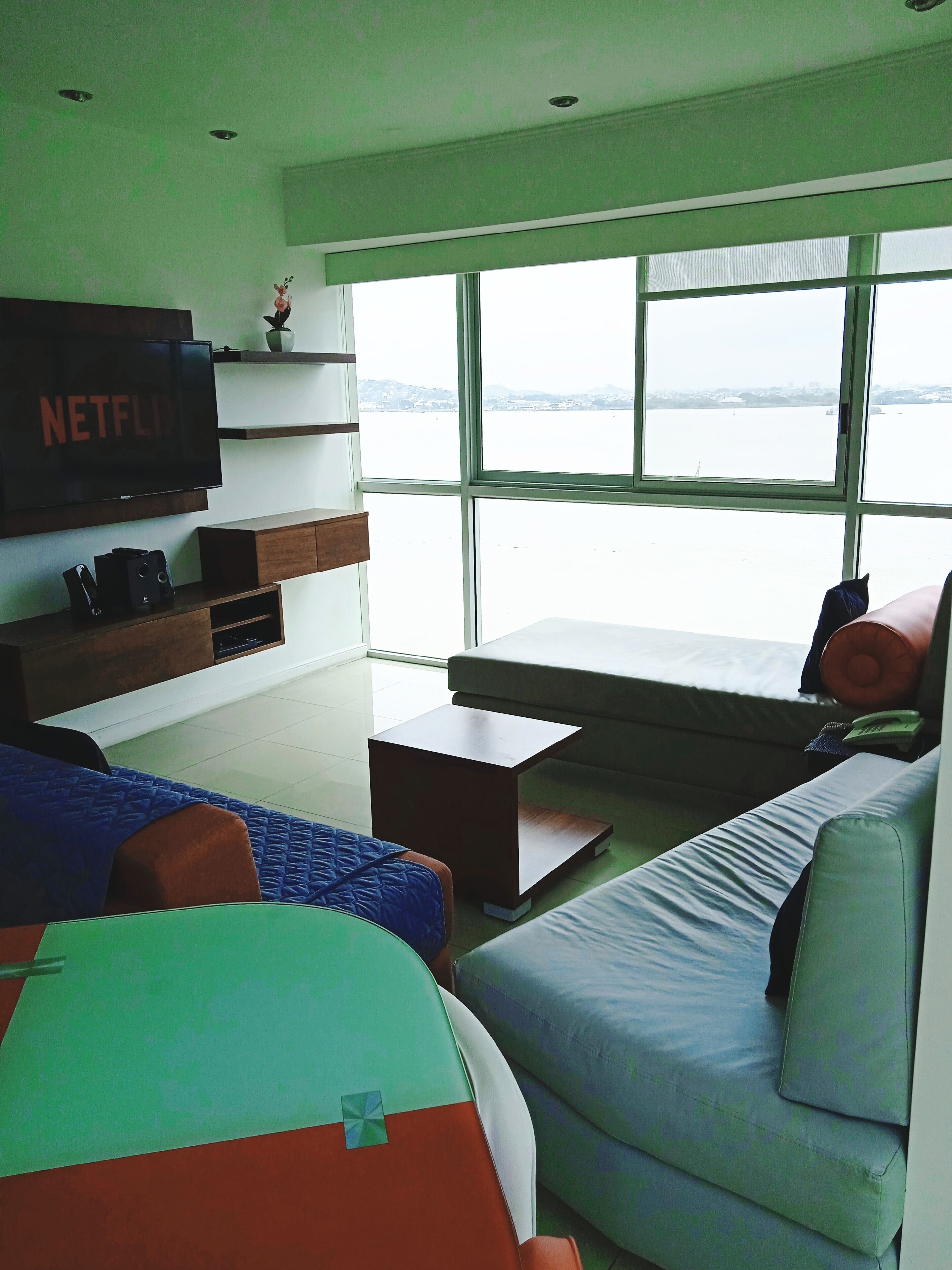 A modern living room with a large window, a flat-screen TV, and a sofa.