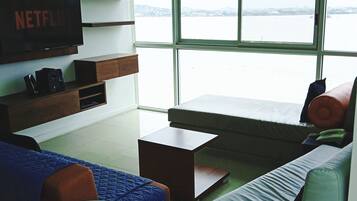 A modern living room with a large window, a flat-screen TV, and a sofa.