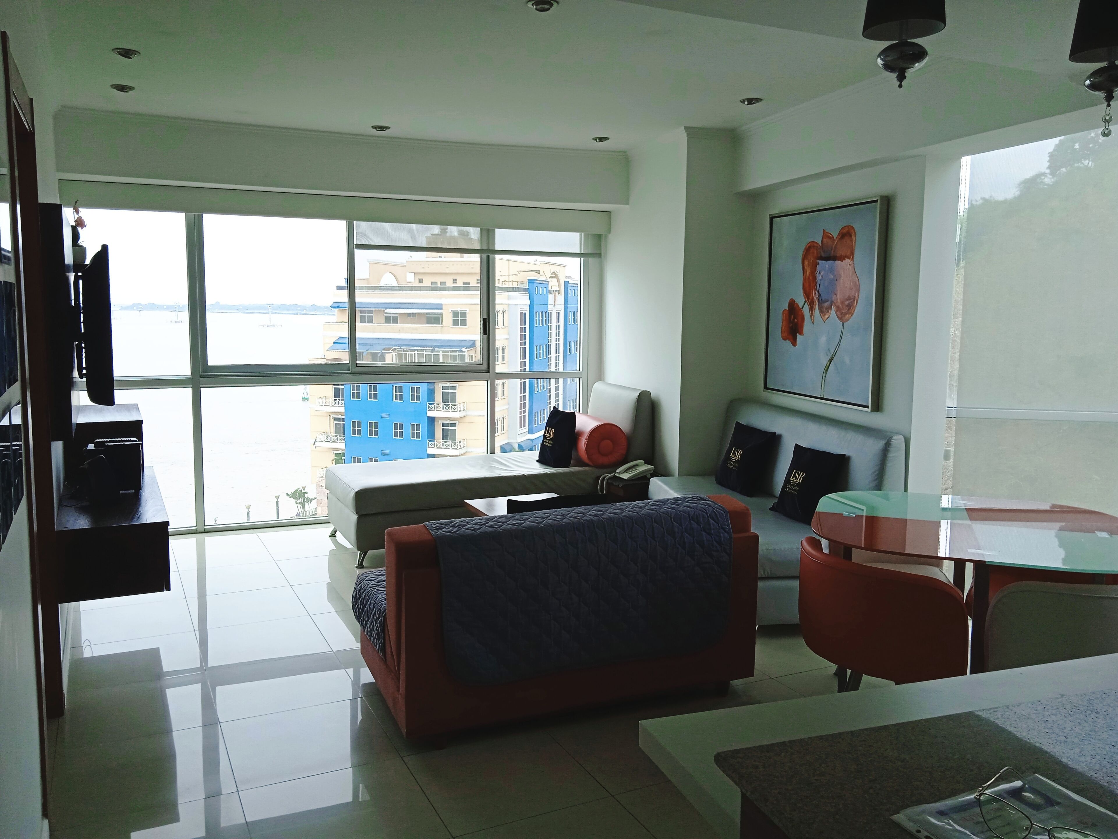 Una habitación de hotel moderna con un gran ventanal, una cama, un escritorio y una silla.