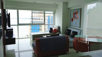 Una habitación de hotel moderna con un gran ventanal, una cama, un escritorio y una silla.