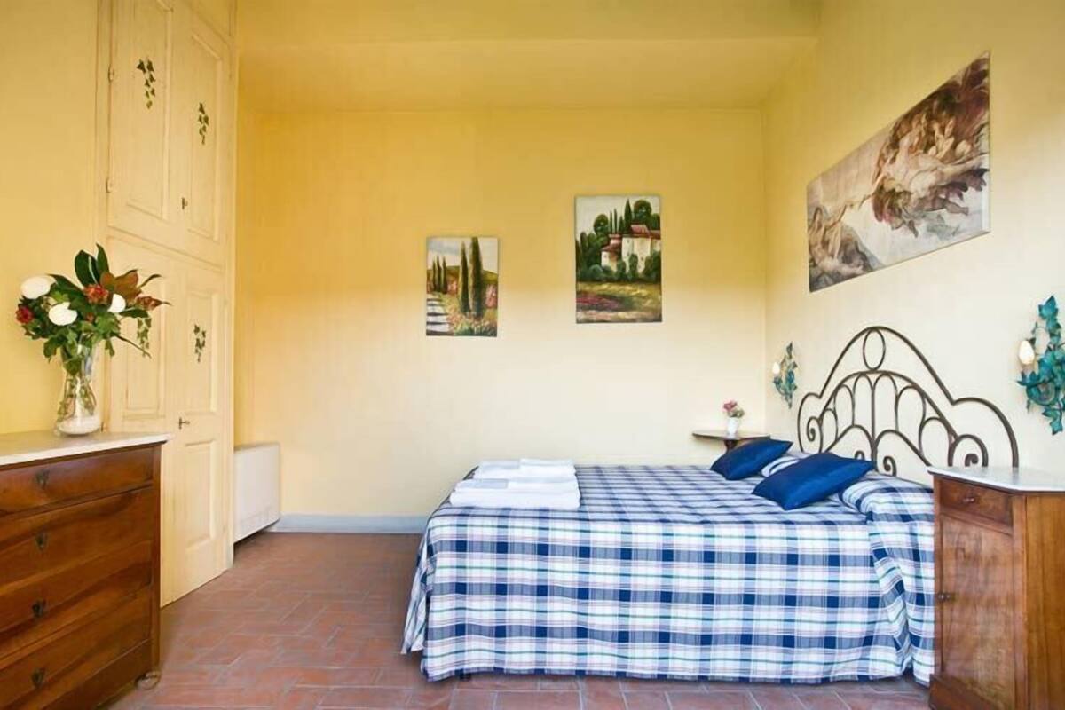 Une chambre à coucher comprenant un lit, une commode, une table de chevet et deux tableaux accrochés au mur.
