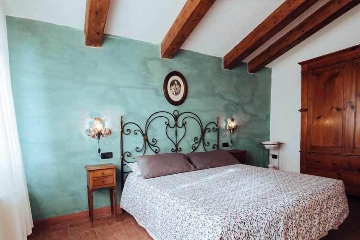 Une chambre à coucher comprenant un lit, une table de chevet, une lampe fixée au mur et une armoire en bois.