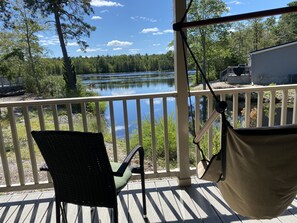 A wooden deck with a chair and a hammock overlooking a lake. - Swan Lake Resort Rentals (Absecon)