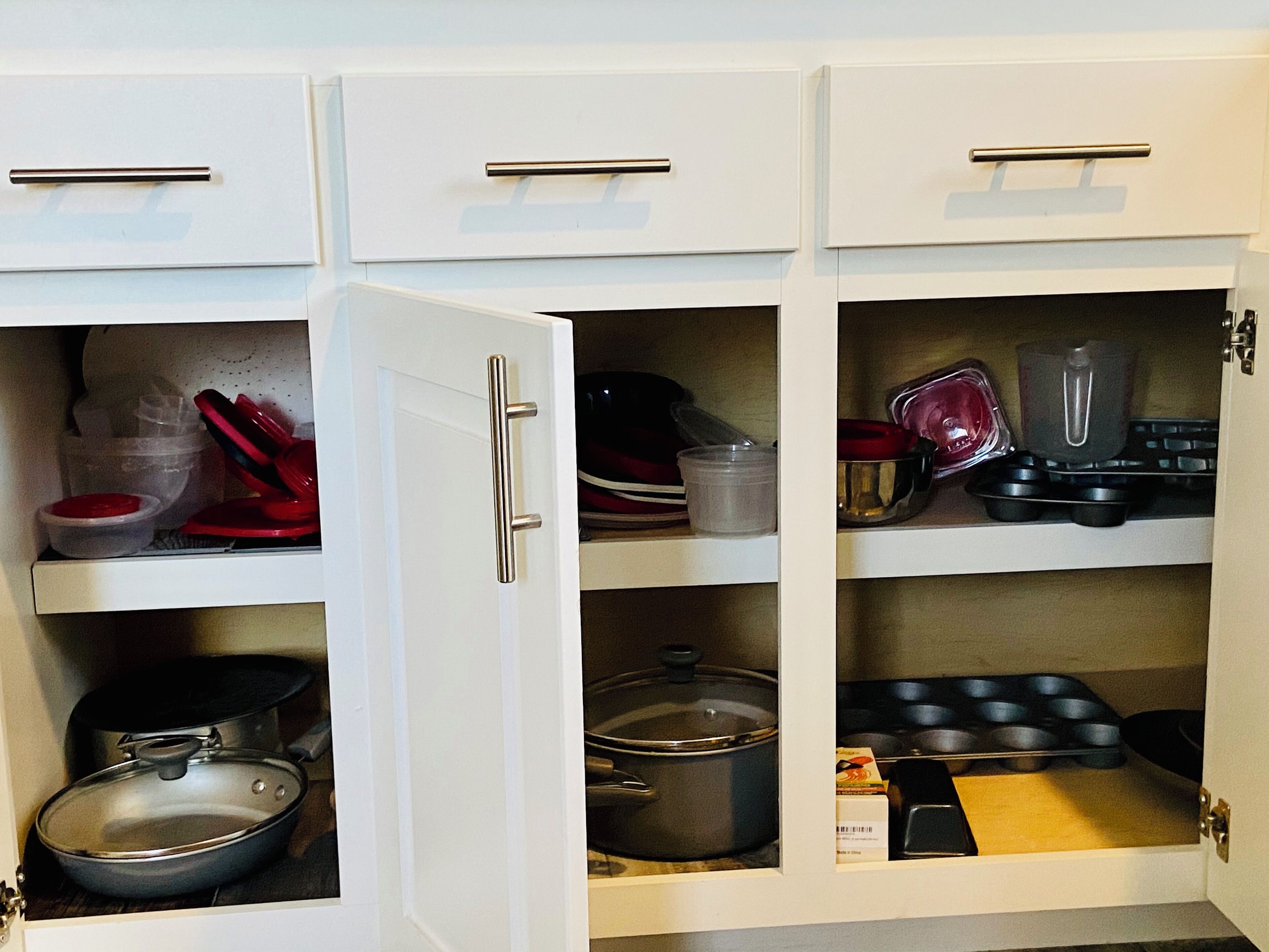 A kitchen with white cabinets, stainless steel appliances, and various kitchenware.