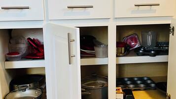 A kitchen with white cabinets, stainless steel appliances, and various kitchenware.