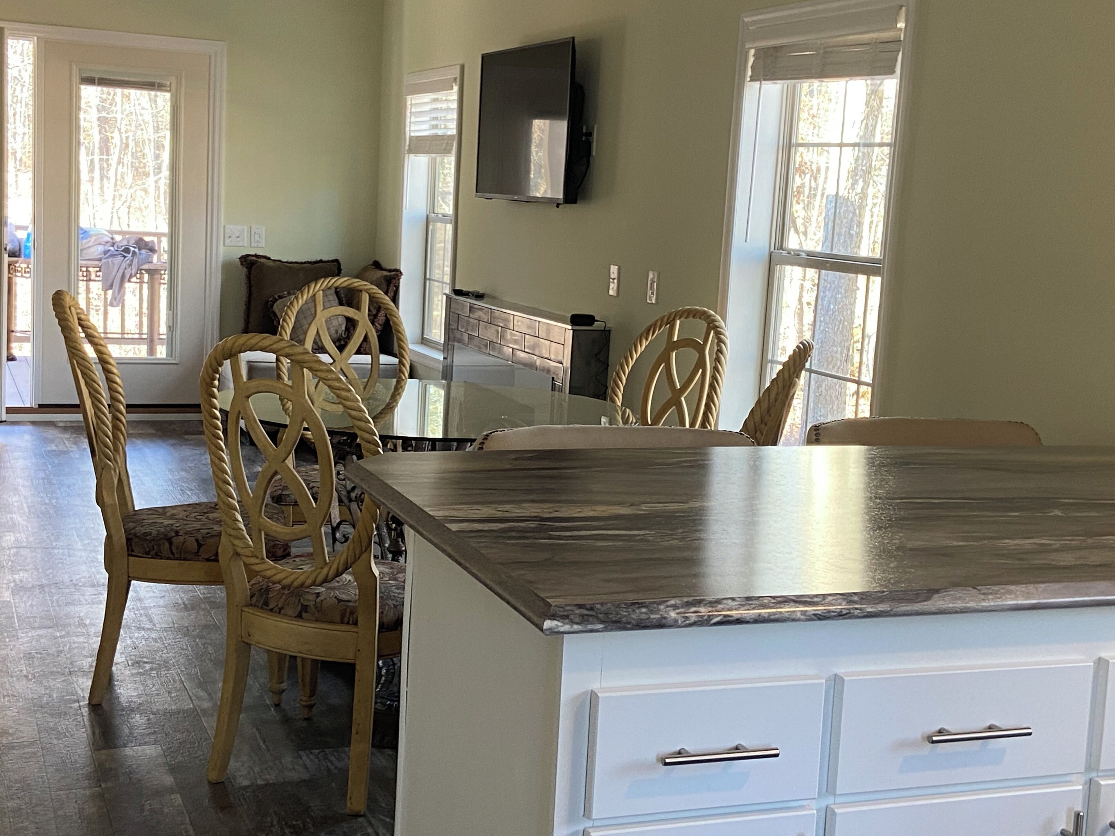 A dining area with a large island, chairs, and a TV mounted on the wall.