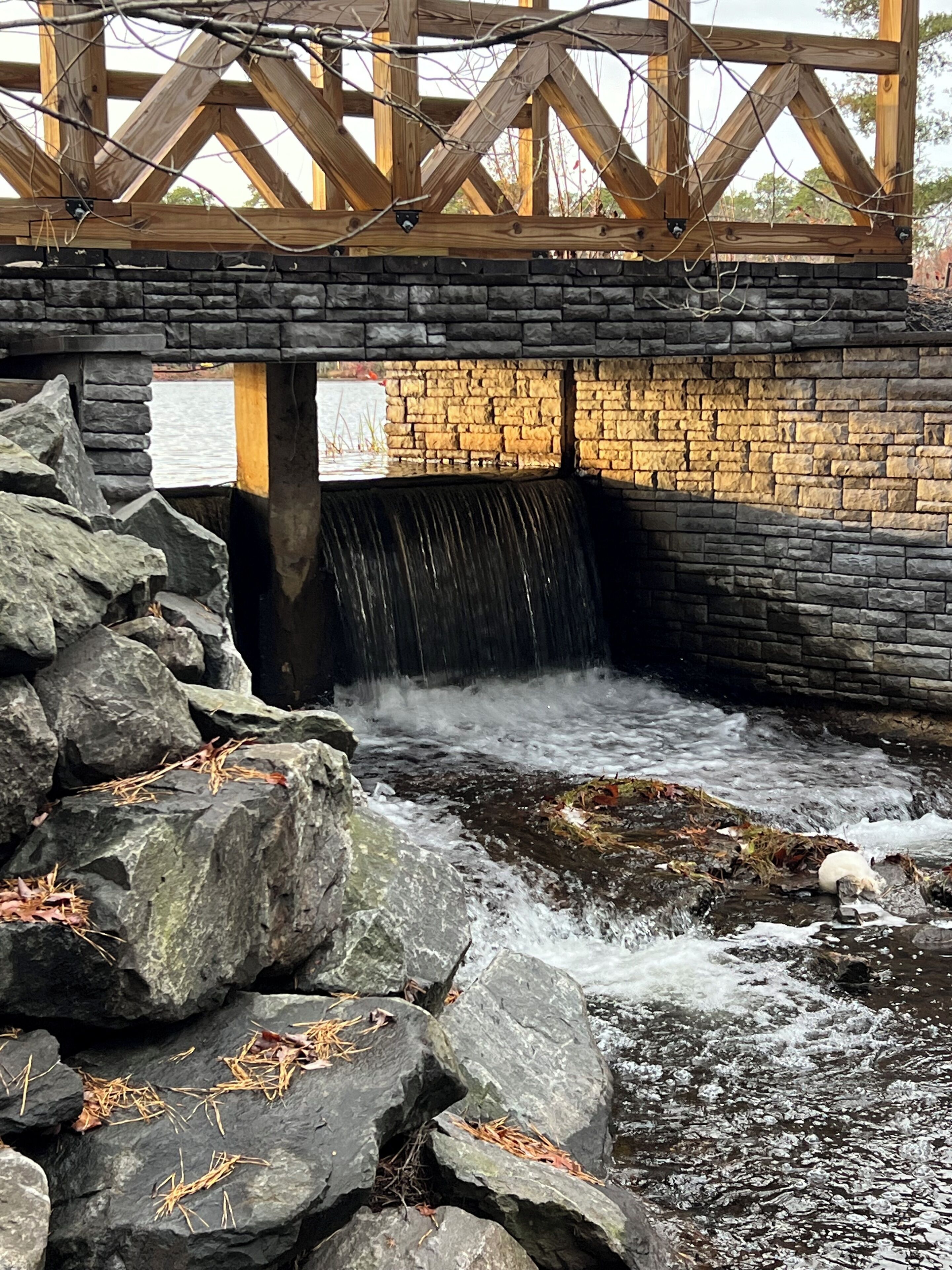 Un pont de pierre avec une petite cascade en dessous.