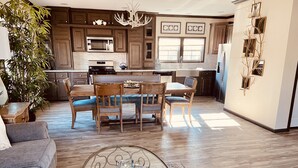 Una cocina moderna con armarios de madera, un comedor con una mesa de centro de vidrio y una planta grande.