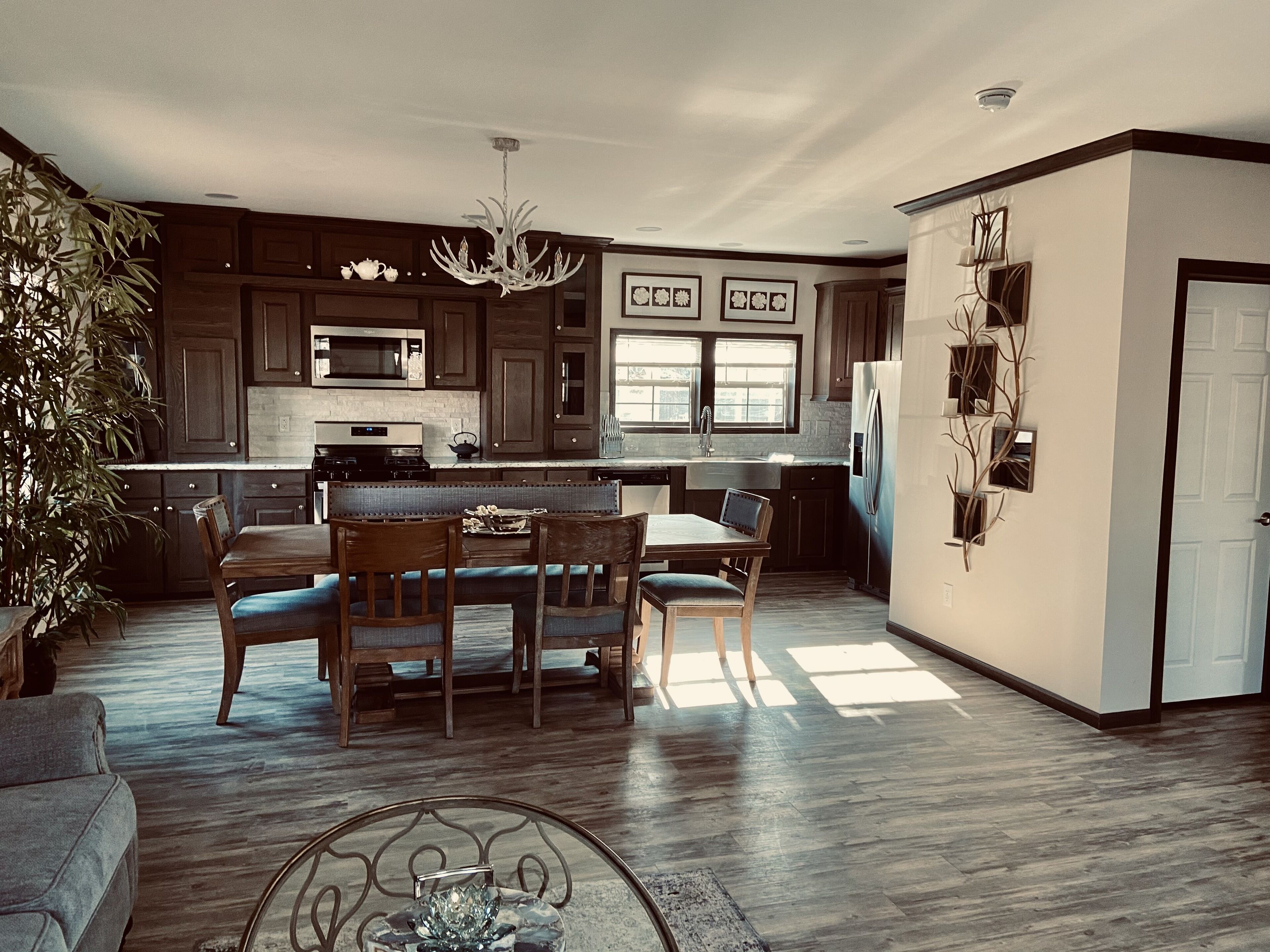 Una cocina espaciosa con armarios de madera oscura, una isla central y un comedor con candelabro.