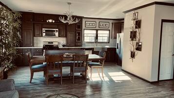 Una cocina espaciosa con armarios de madera oscura, una isla central y un comedor con candelabro.