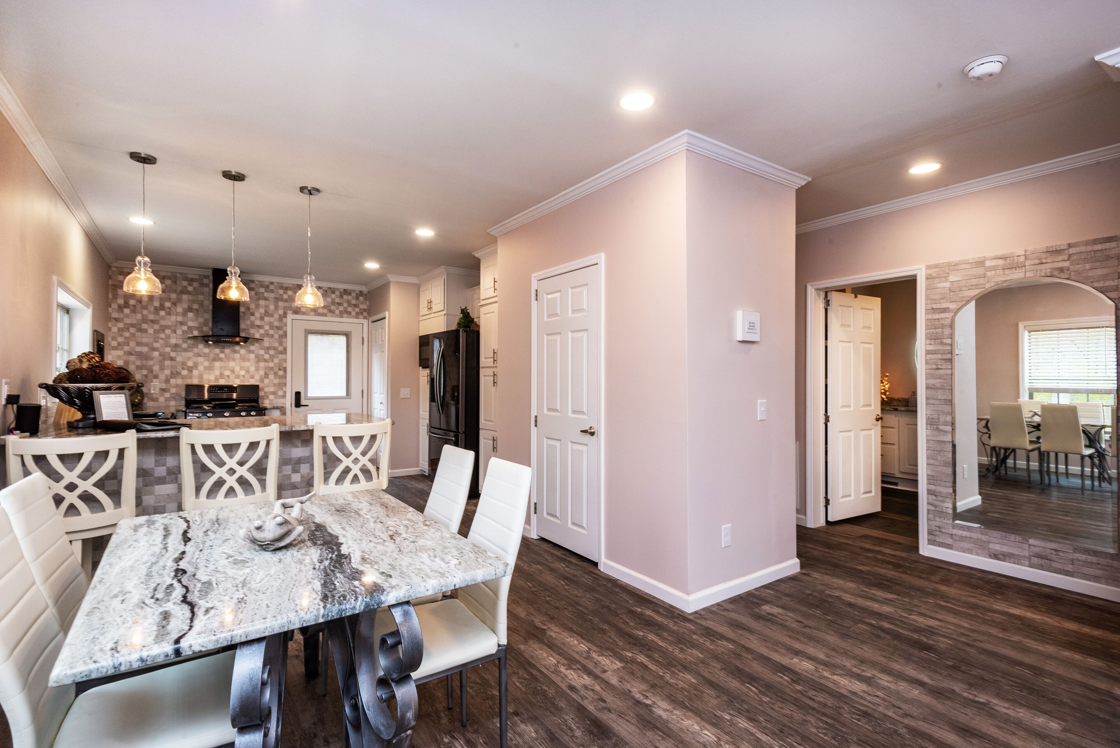 A modern kitchen with white cabinetry, a marble island, and pendant lighting.