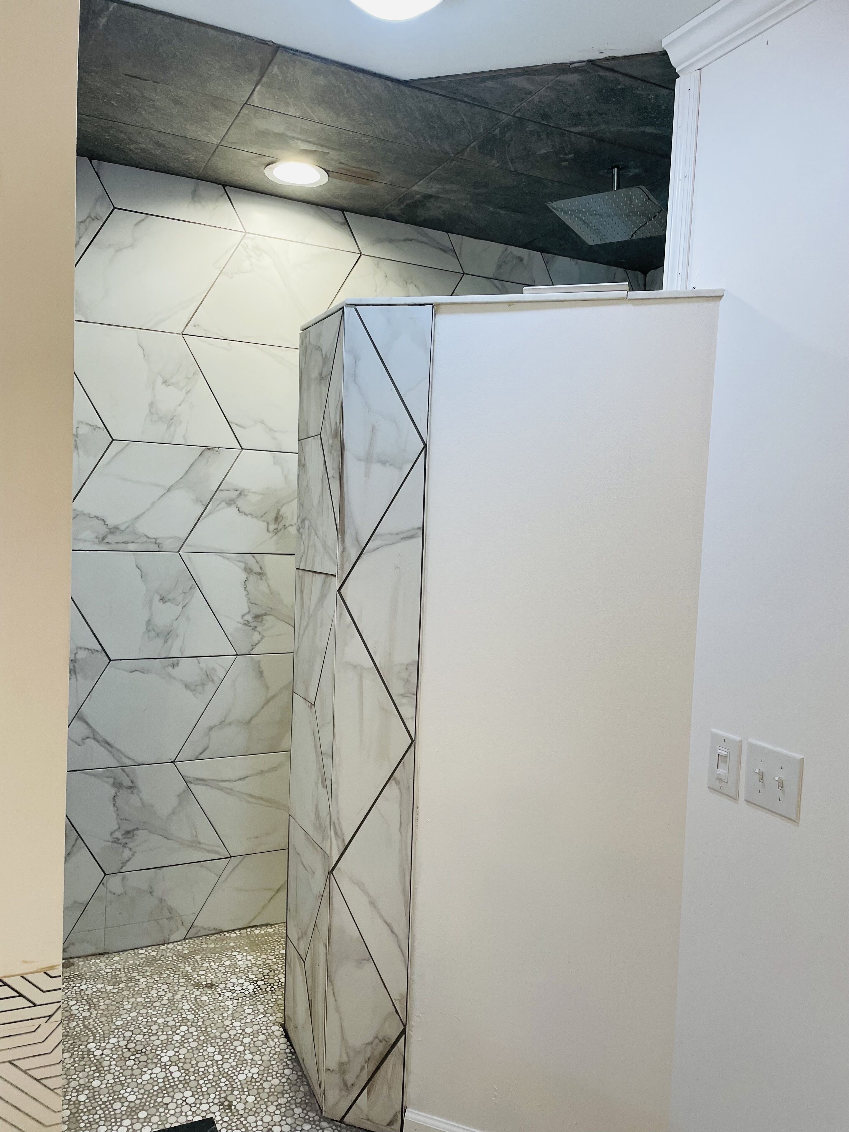 A bathroom with a white tiled wall, a marble-patterned floor, and a white cabinet.