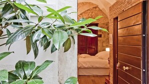 A doorway leading to a room with a bed, a stone wall, and a wooden door. - B&B Il Marchese Del Grillo (Sulmona)