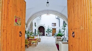 A cozy courtyard with wooden doors, a dining area, and a view of the street. - B&B Il Marchese Del Grillo (Sulmona)