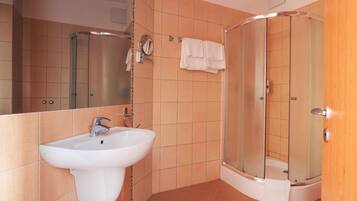 Un baño con lavamanos, espejo y cabina de ducha.