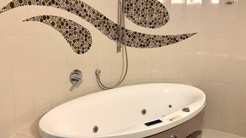 Um banheiro com pia branca, chuveiro com design em mosaico e vaso sanitário.