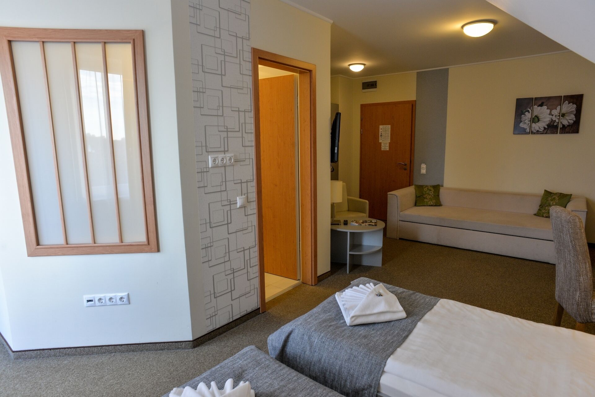 Una habitación de hotel con una cama, un sofá, una mesita y una puerta que da a otra habitación.