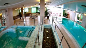 An indoor swimming pool with multiple sections, including a central water feature and a separate pool area. - Granada Konferencia Wellness Sport Hotel (Kecskemet)