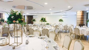 A banquet hall with round tables, gold chairs, and floral centerpieces. - Granada Konferencia Wellness Sport Hotel (Kecskemet)