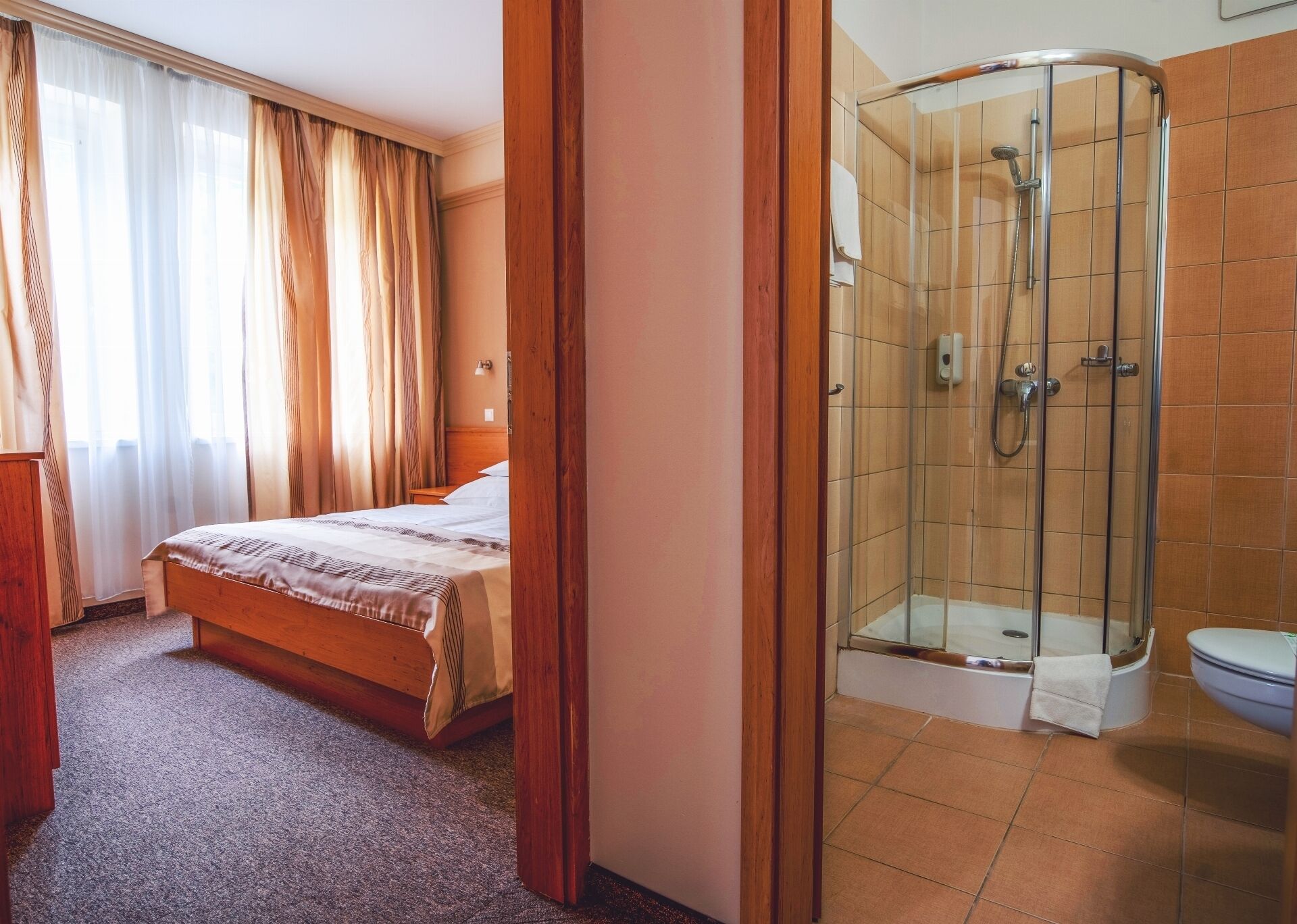 Una habitación de hotel con cama, ducha y inodoro.