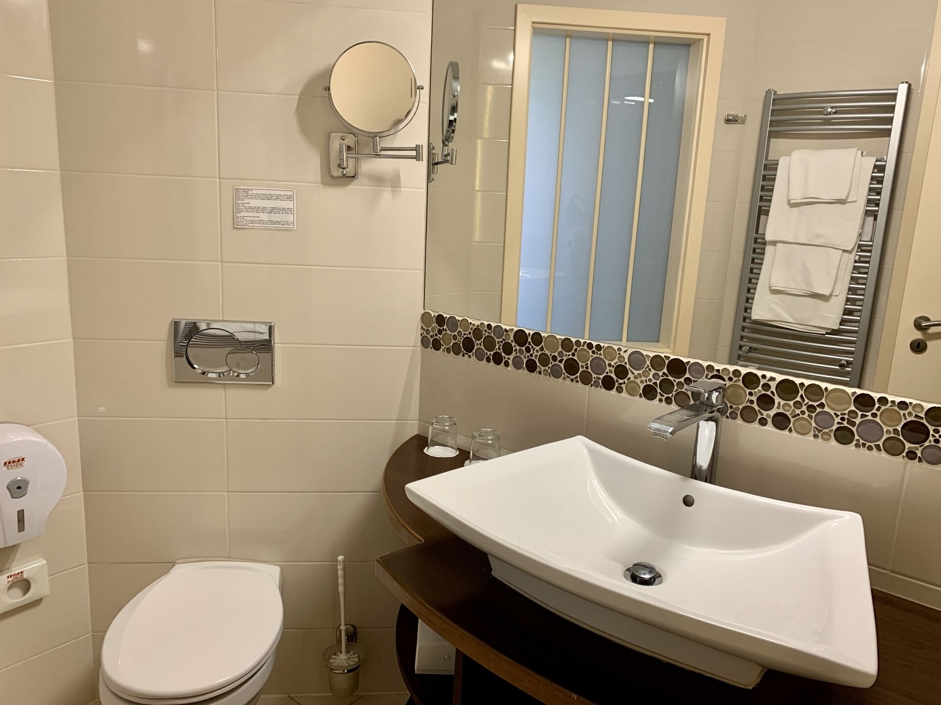 A bathroom with a white sink, a toilet, a mirror, and a towel rack.