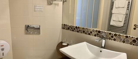 A bathroom with a white sink, a toilet, a mirror, and a towel rack.