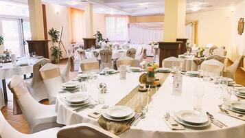 A banquet hall with round tables, white tablecloths, and chairs with gold sashes.