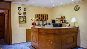 A reception desk with a wooden finish, a clock on the wall, and framed certificates. - Piccolo Sogno Inn (Pompei)
